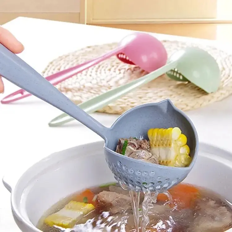 Cucharon gris con colador integrado, usado para sacar maíz y carne de una olla con sopa, mostrando otros dos en fondo.