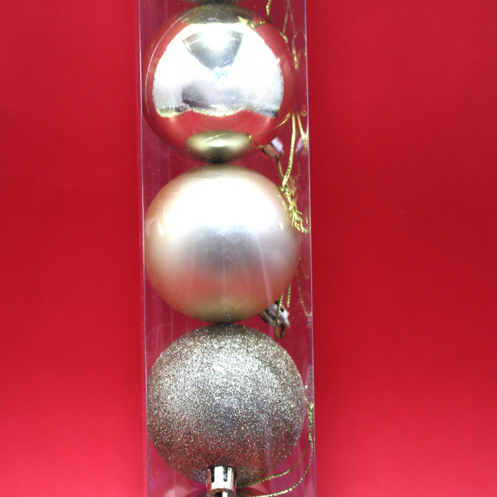 Set de tres bolas navideñas doradas de 6 cm en empaque vertical, con acabados brillante, mate y escarchado, listas para colgar en el árbol de Navidad.