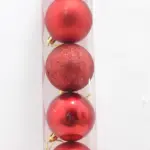 Tubo transparente con cuatro esferas navideñas rojas de seis centímetros: una mate, una con escarcha brillante, una brillante y otra parcial.
