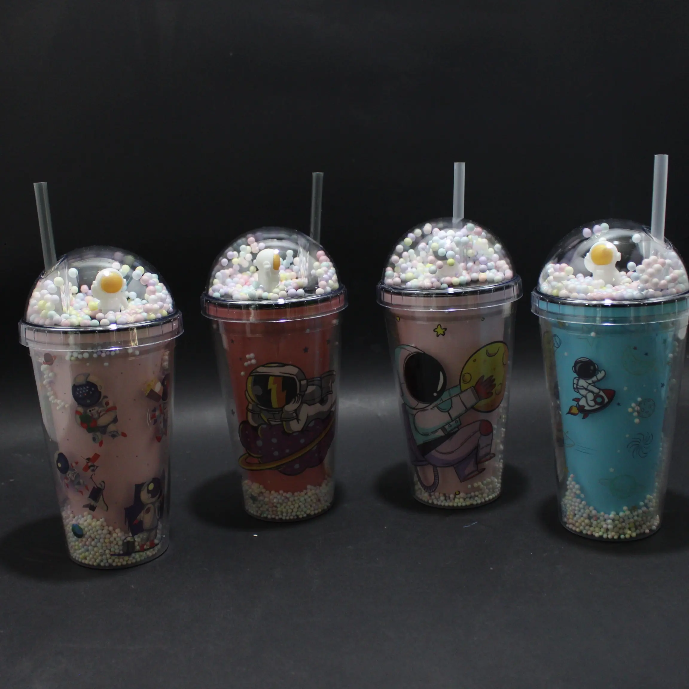Cuatro termos con pitillo y tapa de domo con cuentas y un huevo frito, con diseño espacial de astronautas en tonos rosa y azul.