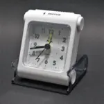Reloj despertador de viaje blanco con esfera analógica y estuche protector transparente de acrílico.