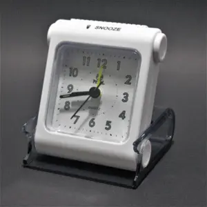 Reloj despertador de viaje blanco con esfera analógica y estuche protector transparente de acrílico.