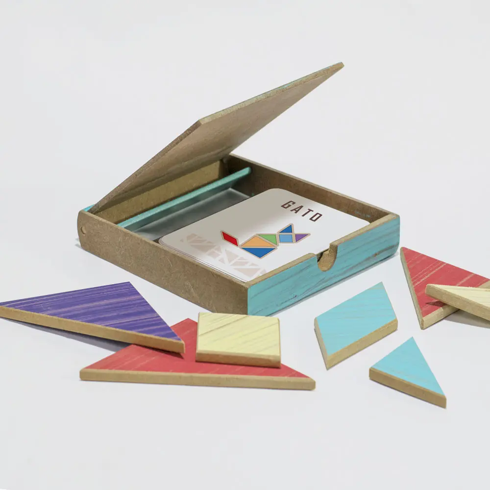 Set de juego Tangram de madera en caja celeste y natural abierta con piezas geométricas dispersas y cartas didácticas.