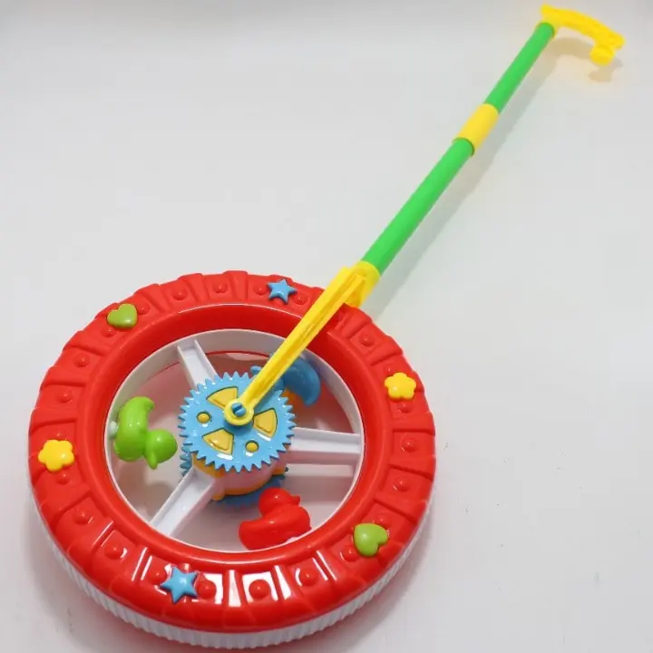 Juguete didáctico de empuje en forma de rueda roja con engranajes azules, mango verde y amarillo, y patitos de goma adentro.