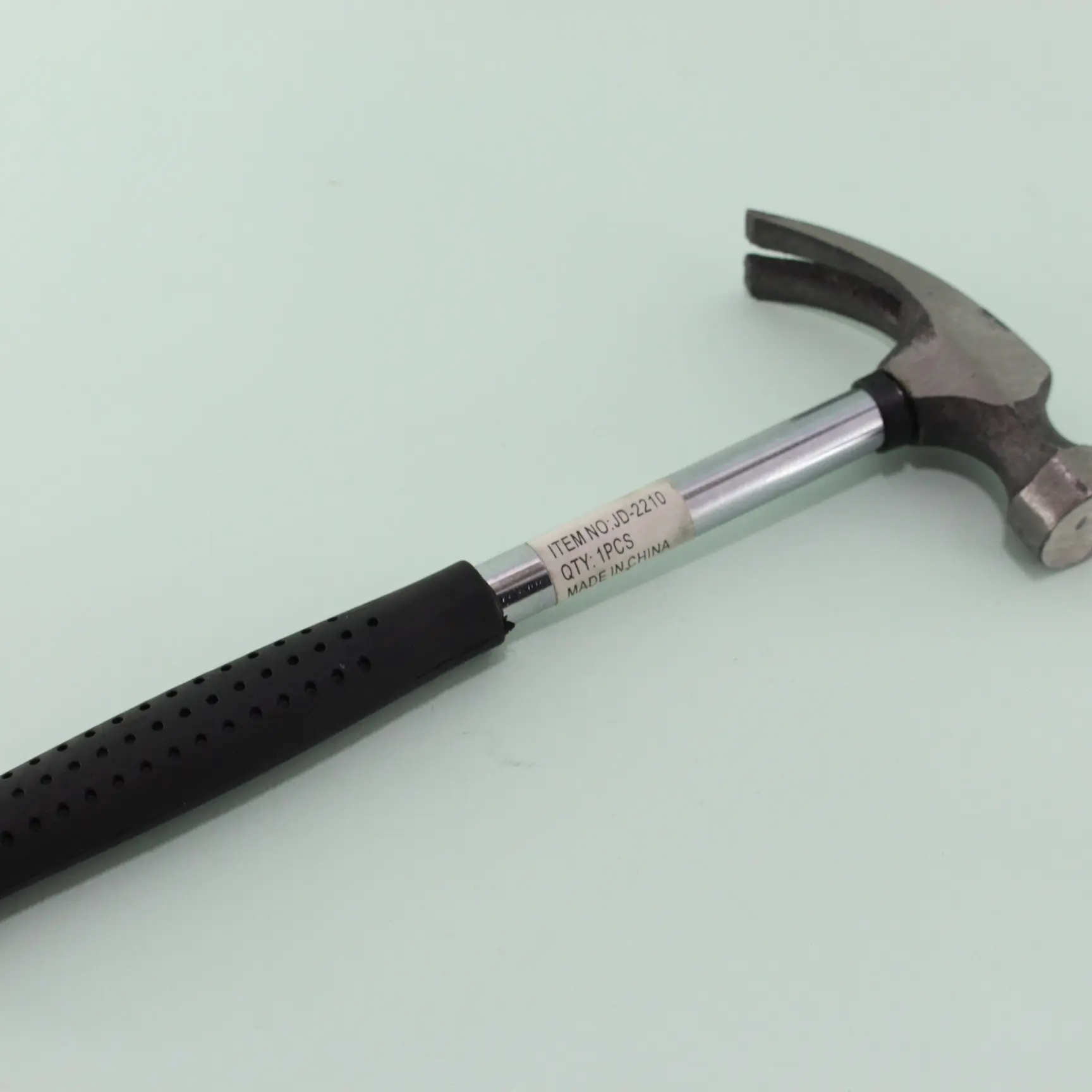 Martillo de carpintero con mango ergonómico negro texturizado, eje metálico plateado y cabeza de acero con uña, visto en ángulo diagonal.