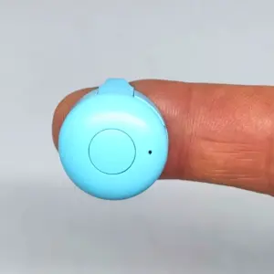 Anillo controlador Bluetooth celeste con botón central y LED indicador apoyado en la punta de un dedo.