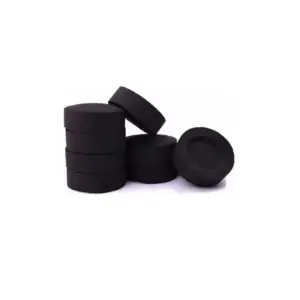 Pila de diez pastillas de carbón litúrgico negro, circular y compacto, con un elemento inclinado y otra pastilla independiente con cavidad cóncava superior.