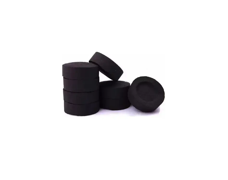 Pila de diez pastillas de carbón litúrgico negro, circular y compacto, con un elemento inclinado y otra pastilla independiente con cavidad cóncava superior.