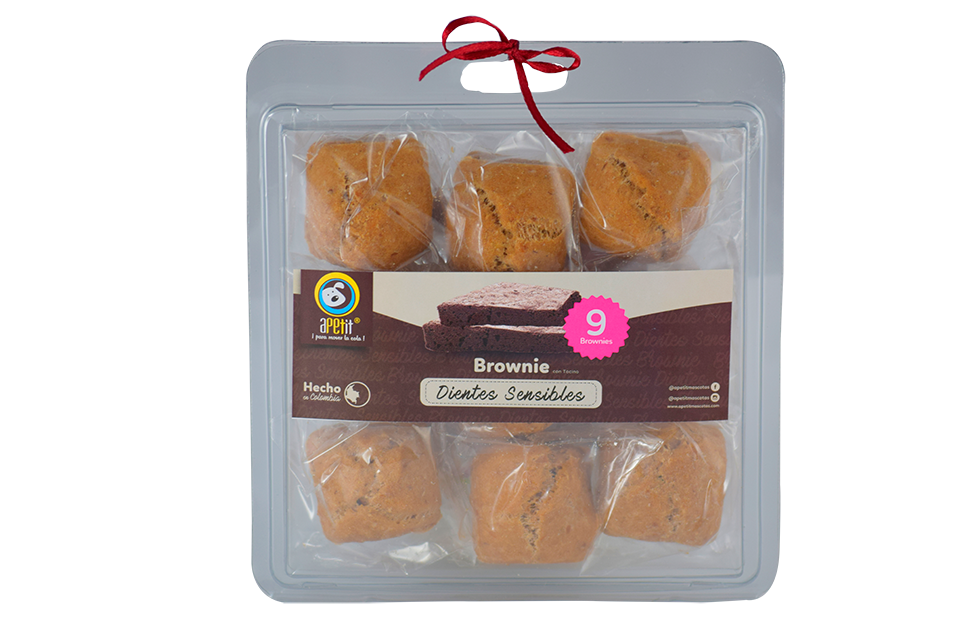 Caja transparente con 9 snacks blandos marrones empaquetados individualmente para perros con sensibilidad dental y cinta roja decorativa.