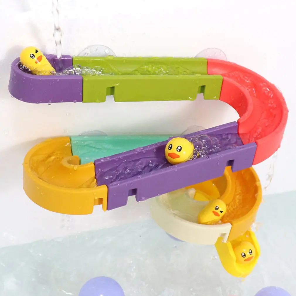 Set de baño infantil multicolor con toboganes en zigzag y patitos amarillos deslizándose bajo un chorro de agua.