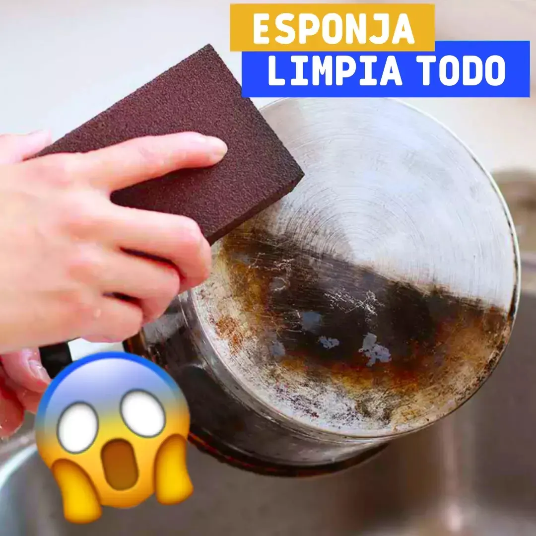 Mano usando esponja de limpieza marrón oscuro para remover grasa y residuos quemados de una olla de acero inoxidable.