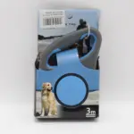 Correa retráctil para perro de 3 metros azul y gris en su caja de presentación con de Golden Retriever en la playa.