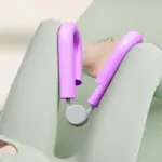 Mujer acostada sobre esterilla verde usando un ejercitador de muslos y piernas morado entre las rodillas para fortalecer los músculos pélvicos