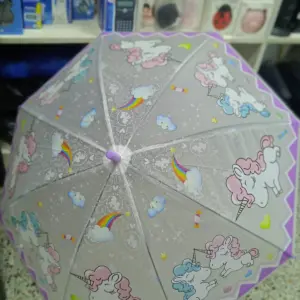 Sombrilla infantil gris con estampado de unicornios, arcoíris y nubes, borde morado y estructura transparente.