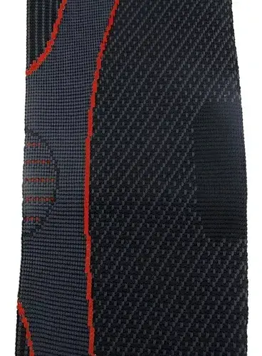Detalle del tejido elástico de compresión de la codera ortopédica gris oscuro con textura de puntos y costura roja.