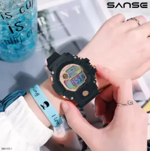 Reloj deportivo digital negro con pantalla multicolor y detalles dorados en la muñeca de una mujer.