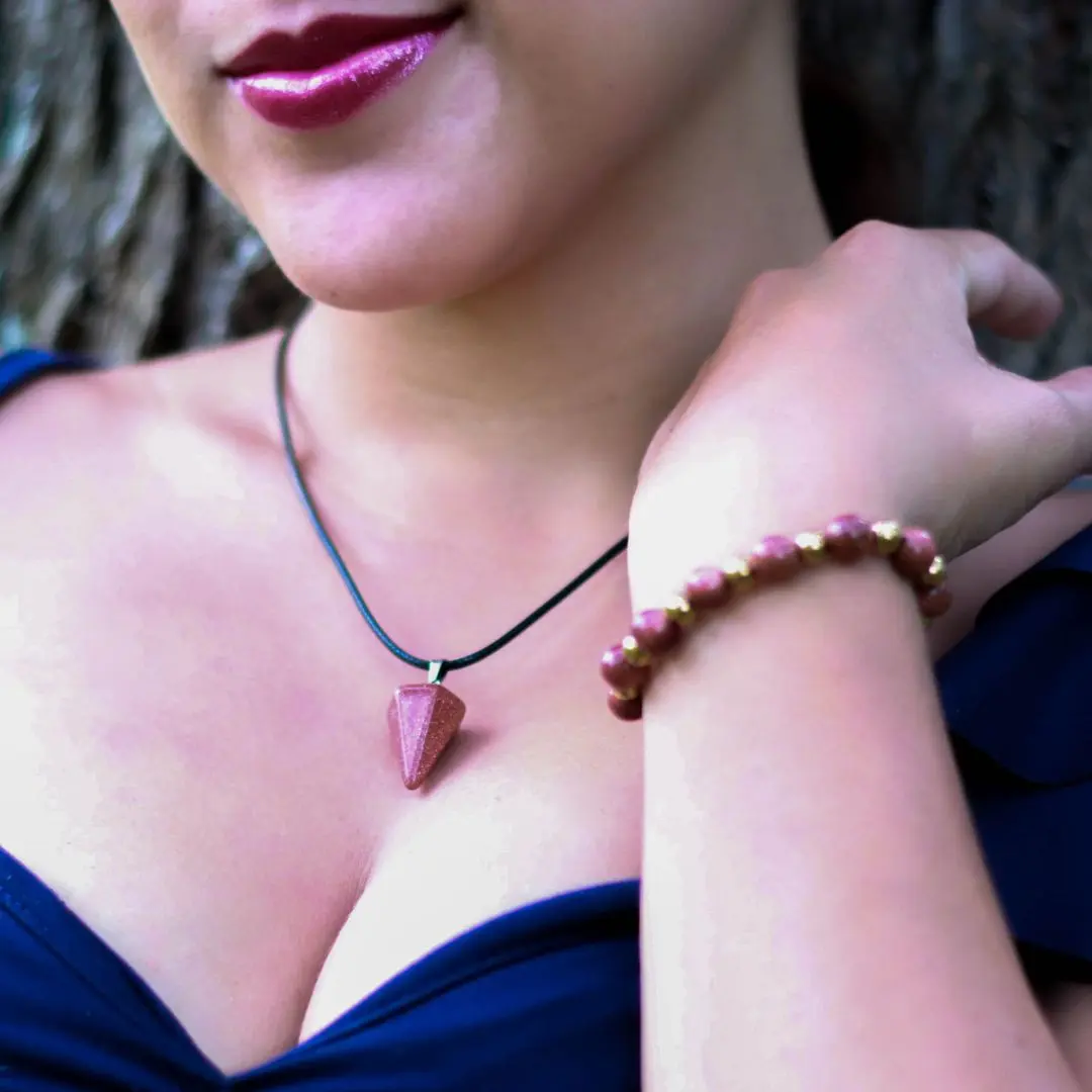 Set de collar con péndulo facetado y pulsera artesanal de piedra natural brillante color marrón cobrizo con cuentas doradas.
