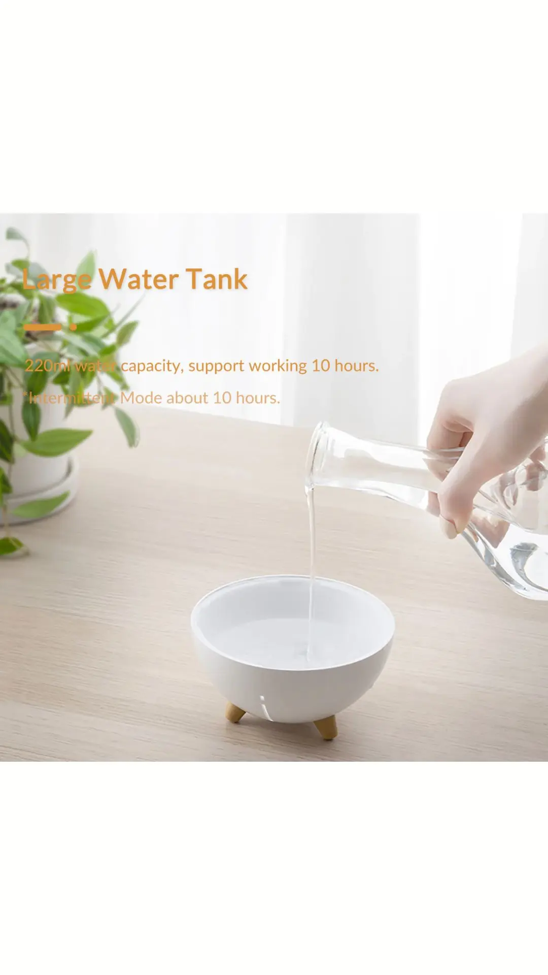 Humidificador blanco de diseño redondo con patas de madera sobre mesa, mientras una mano vierte agua desde una jarra de vidrio.