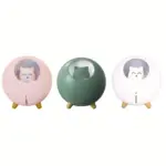 Tres humidificadores portátiles en colores rosado, verde y blanco con diseño redondo de gato, luz nocturna y patas de apoyo.