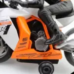 Detalle lateral de moto a control remoto blanca y naranja con piloto en traje negro, motor plateado y calcomanías deportivas R31.