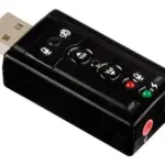 Adaptador de sonido USB externo negro con conector USB tipo A, botones físicos de volumen, silenciamiento y puertos jack de 3.5 mm para audio y micrófono.