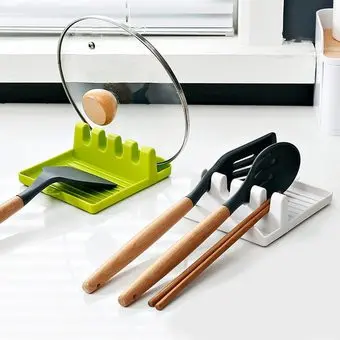 Soportes organizadores de cocina en verde lima y blanco con ranuras para tapas y utensilios de mango de madera, sobre encimera blanca.