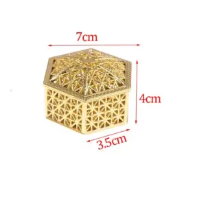 Mini caja hexagonal de metal dorado con diseño calado geométrico de 7 cm de ancho, 4 cm de alto y 3.5 cm de profundidad.