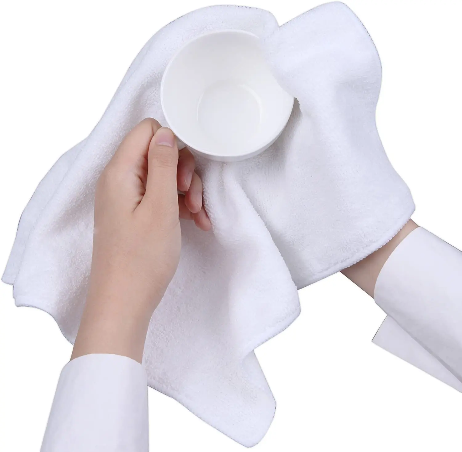Vista cenital de manos sosteniendo una taza blanca sobre un paño de microfibra blanco, resaltando su textura suave y uso multiuso.