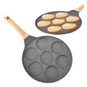 Sartén antiadherente gris con siete cavidades circulares, mango de madera y acabado moteado, mostrada vacía y con panqueques cocinándose en su interior.