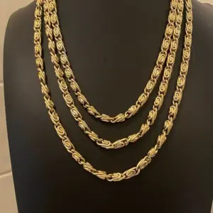Set de dos collares dorados de acero inoxidable con eslabón caracol, de diferentes largos, sobre un busto de exhibición negro.