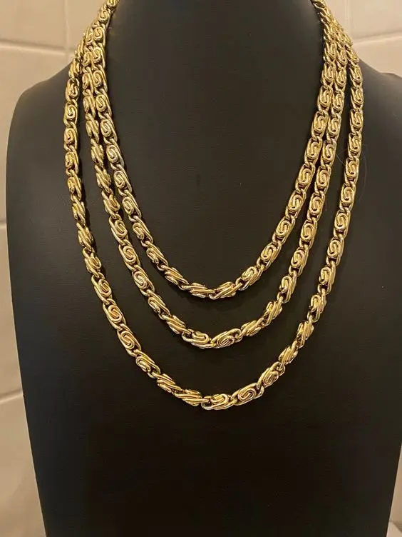 Set de dos collares dorados de acero inoxidable con eslabón caracol, de diferentes largos, sobre un busto de exhibición negro.
