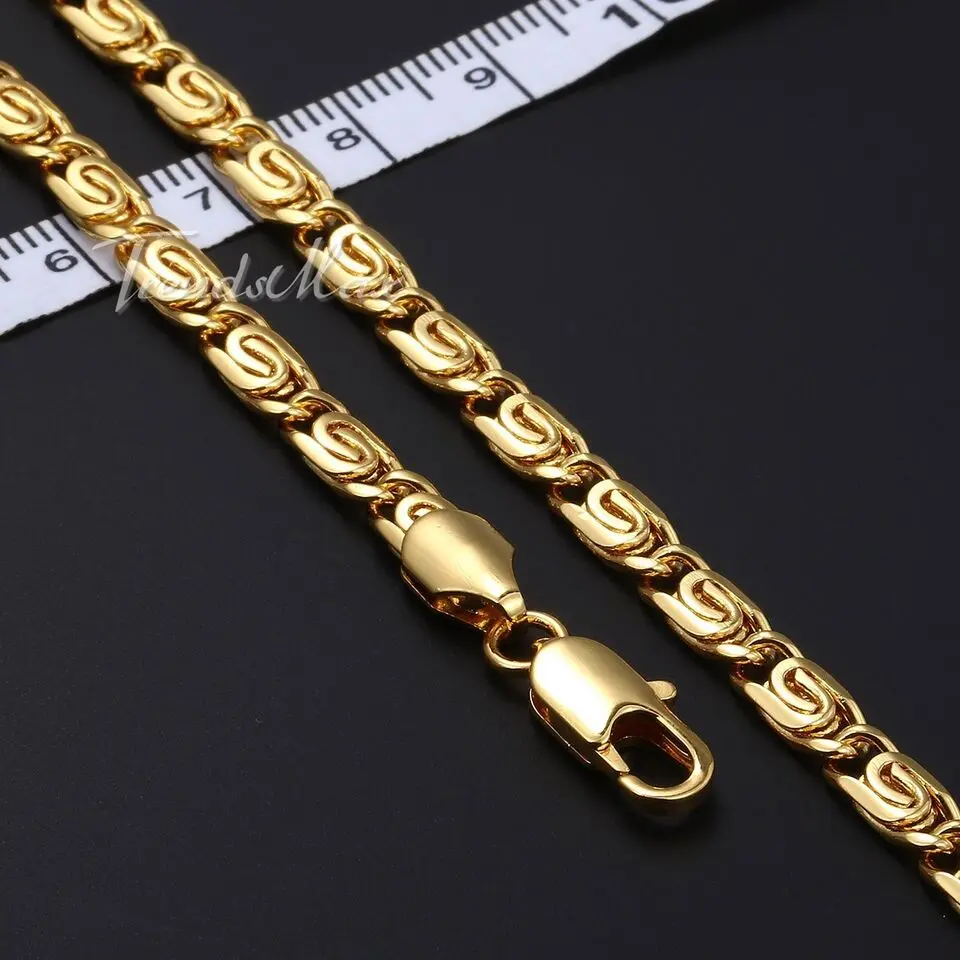 Set de dos collares dorados de eslabón caracol con broche de langosta, junto a una cinta métrica de referencia sobre fondo negro.