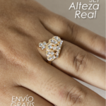 Anillo dorado con pedrería brillante en forma de corona y circonias incrustadas, puesto en el dedo de una mano