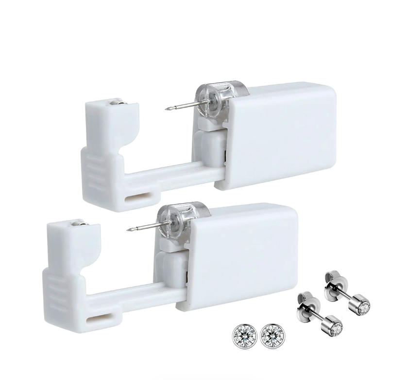 Dos dispositivos blancos desechables para perforar orejas, con aretes brillantes incluidos.