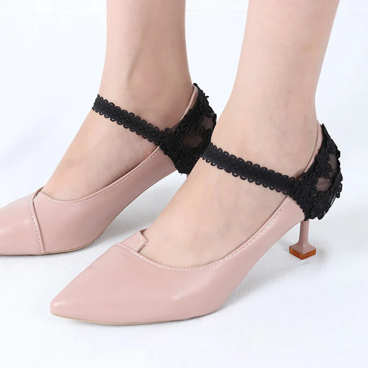 Par de correas negras de encaje elástico para tacones, con diseño floral transparente en el talón, ajustadas a zapatos rosados.
