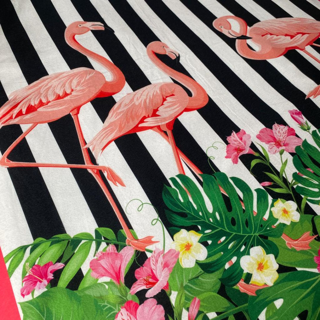 Manta polar fleece con diseño tropical de flamencos rosas, hojas de palma verdes y flores sobre fondo de rayas blanco y negro.