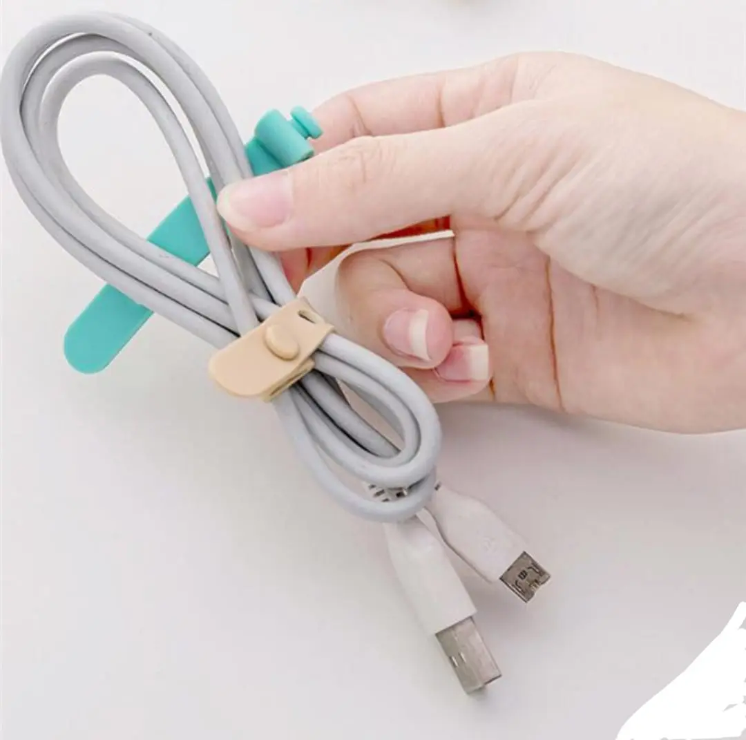 Mano sujetando un cable gris enrollado con dos broches organizadores de silicona en colores turquesa y beige para evitar enredos.