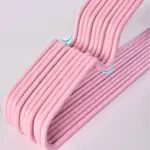 Juego de ganchos metálicos color rosa con acabado antideslizante, apilados para optimizar el espacio en el armario.