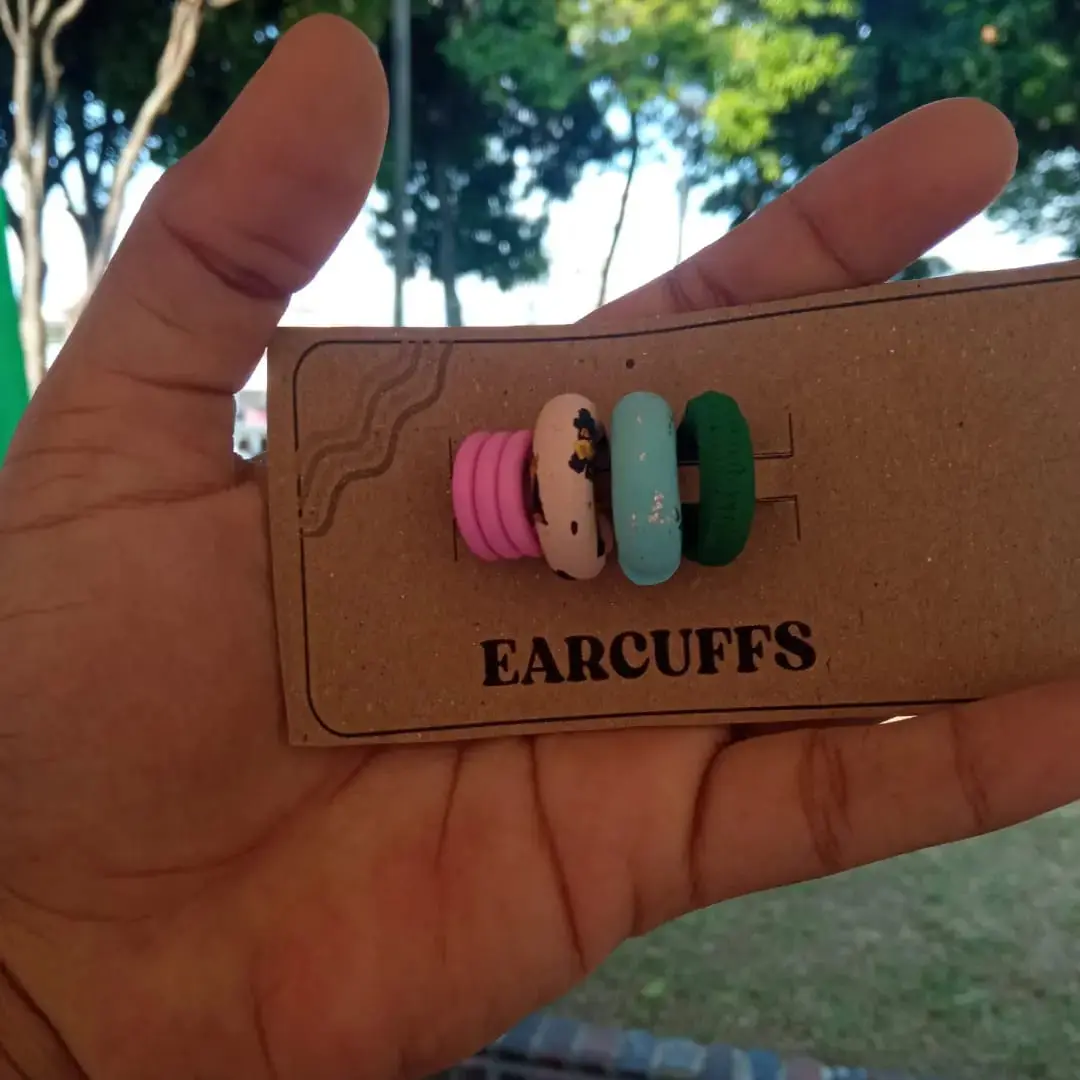 Set de cuatro earcuffs artesanales de arcilla polimérica en colores rosa, beige con estampado, turquesa con brillo y verde oscuro sobre soporte de cartón.