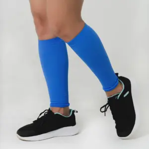 Pantorrillera de compresión azul brillante para mujer, usada en una pierna adelantada, con zapatilla deportiva negra y suela blanca.