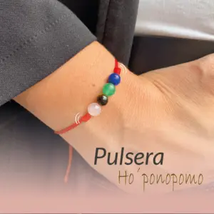 Pulsera Ho'oponopono con hilo rojo ajustable y cuatro piedras naturales en tonos azul, verde, negro y rosa, usada en la muñeca para meditación.