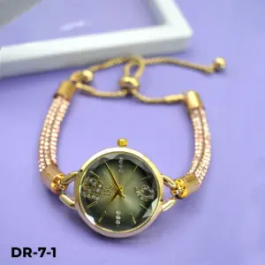Reloj análogo dorado con esfera oscura y cristales, pulsera de pedrería y cadena ajustable con cierre corredizo sobre fondo lila.