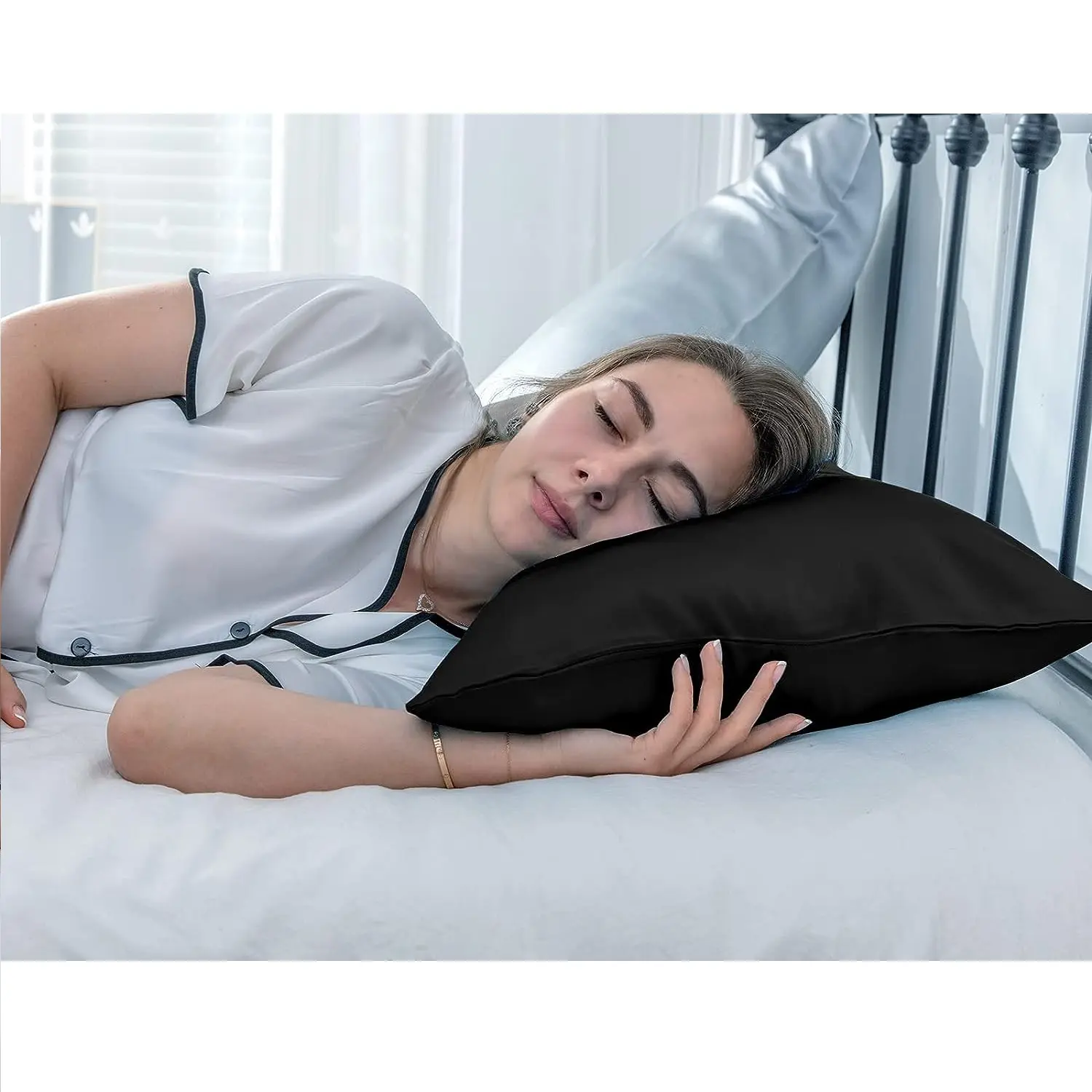 Mujer durmiendo de lado sobre una funda para almohada negra de satín brillante, apoyando la cabeza plácidamente en la cama.