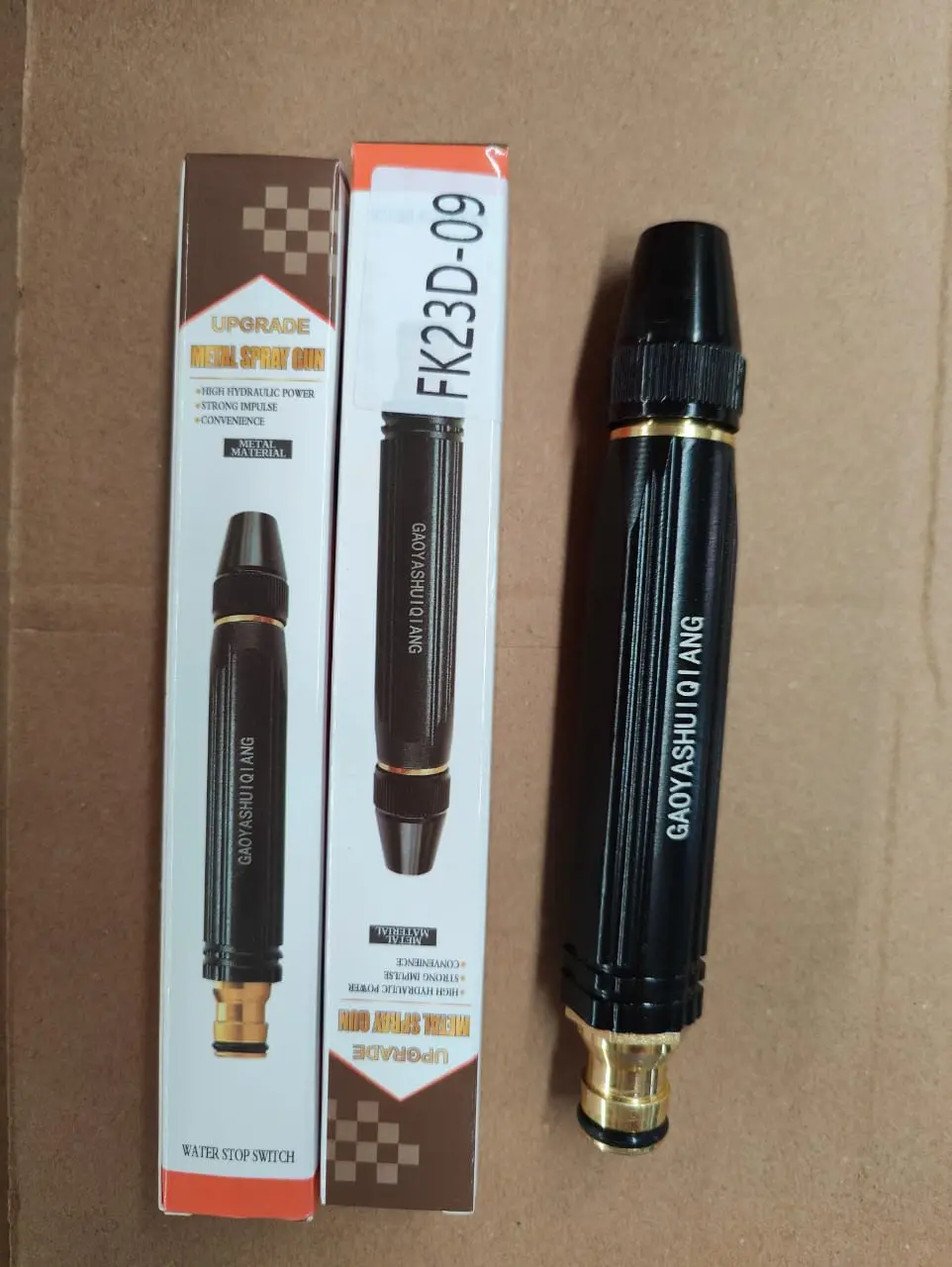 Boquilla de manguera de alta presión metálica negra con conector dorado, mostrada junto a su caja de empaque y etiqueta de referencia FK23D-09.