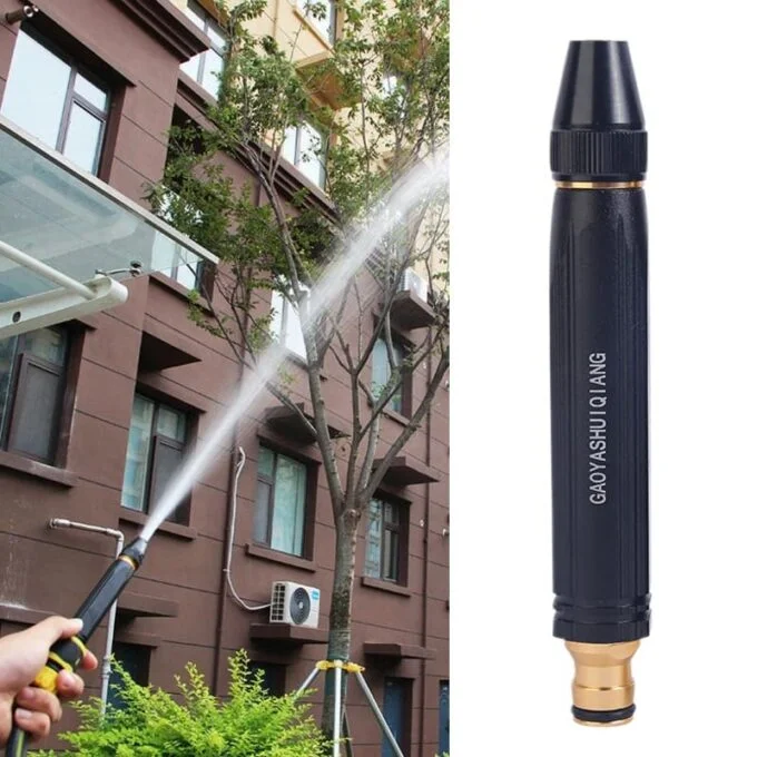 Boquilla de manguera de alta presión negra con grabado de letras blancas y conector dorado, usada para arrojar chorro de agua hacia un árbol y edificio.