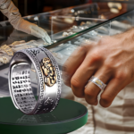 Anillo ancho de acero plateado con figura Pixiu dorada y patrón griego, con grabado interno, mostrado en primer plano y en uso.