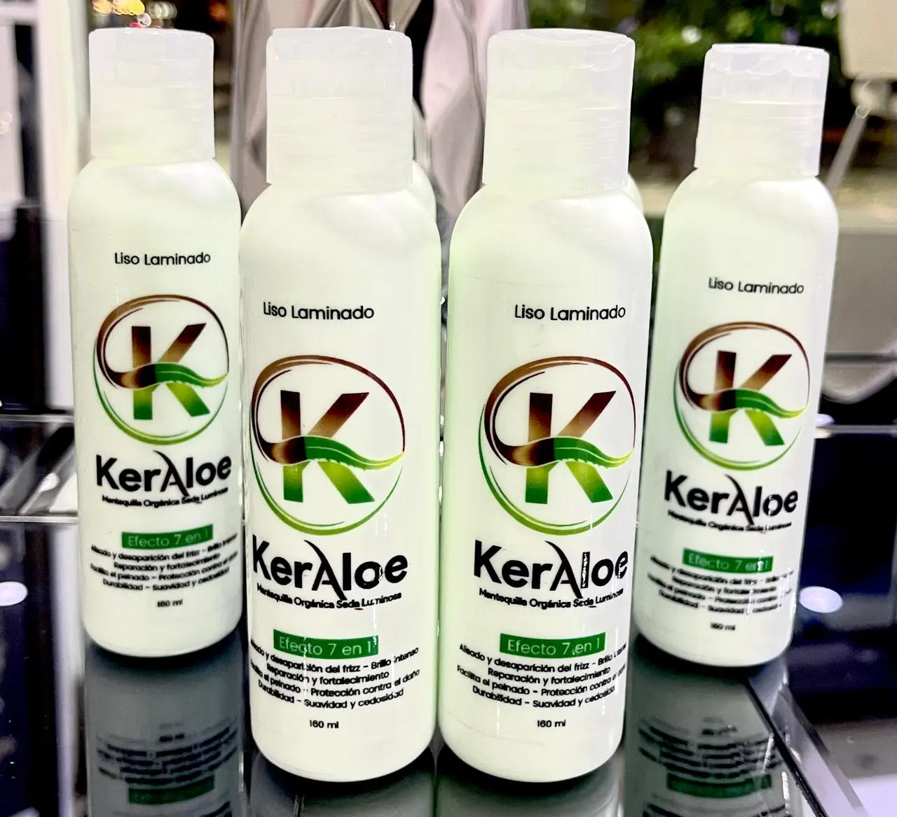 Cuatro envases blancos de 160 ml de mantequilla capilar Keraloe con efecto 7 en 1, alineados sobre una superficie brillante para tratamiento alisador.