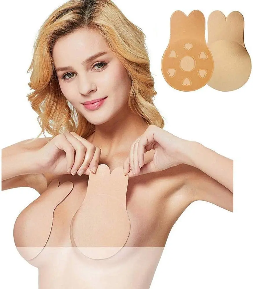 Mujer rubia aplicando par de sujetadores adhesivos color piel con diseño de orejas de conejo para levantamiento de busto sin tirantes