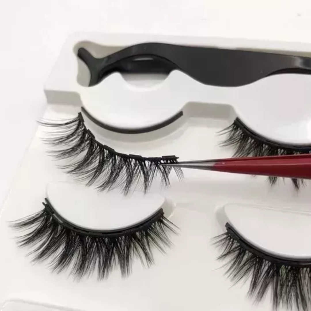 Set x2 pestañas postizas magnéticas negras, aplicador negro en estuche blanco y pinza roja sosteniendo una pestaña.