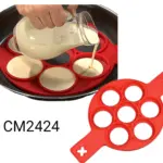 Molde de silicona rojo con siete cavidades circulares para cocinar pancakes o huevos, mostrado en uso sobre un sartén y como pieza independiente.
